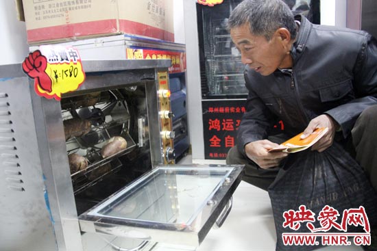 一名科技會員在看一臺自動(dòng)化烤紅薯機(jī)器