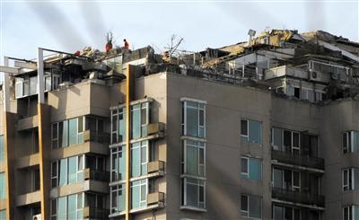 　　昨日，身穿橘黃色馬甲的工作人員在人濟(jì)山莊樓頂拆除違章建筑。新京報(bào)記者 吳江 攝