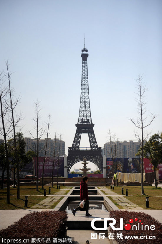 　2014年3月21日，杭州天都城，農(nóng)民在山寨埃菲爾鐵塔下耕作。圖片來源：東方IC