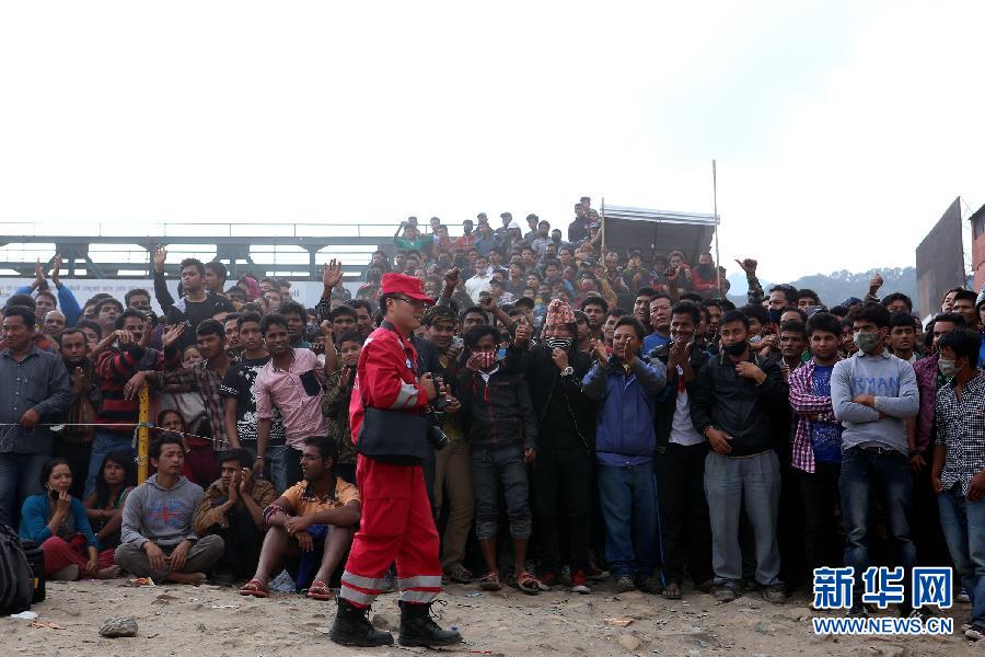 圍觀的尼泊爾民眾在中國國際救援隊成功搜救出幸存者后向搜救隊員歡呼致意。