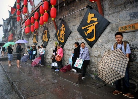 　4月29日上午11時20分，一些游客和古城當?shù)氐木用穸阍谝粋€酒吧的屋檐下避雨。這些當?shù)鼐用褚詾橛慰团恼罩\生，一場降雨讓他們的生意更加清淡。