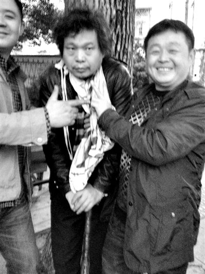 兩名接訪人員與患有癌癥的訪民段新德合影時，面帶笑容擺出勝利的手勢。