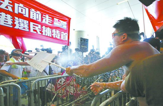 17日，在香港立法會(huì)外，一名反對(duì)政改的男子向支持派人群投擲標(biāo)牌。