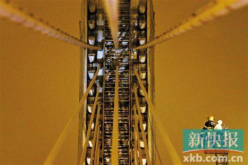 截至今日零時(shí)，男子仍未有下橋舉動(dòng)。圖為公安和消防人員乘消防云梯在高空上和男子交談。