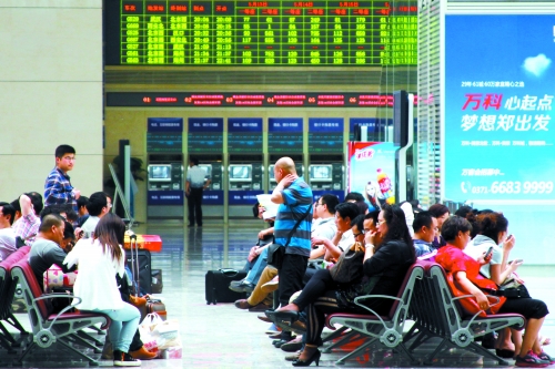 候車大廳溫度很高，一名乘客一手扇風、一手擦汗