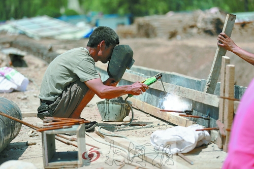 　正午陽(yáng)光下，工地上的焊接工人還在認(rèn)真工作。