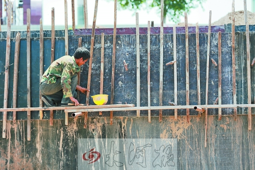 　　烈日下，狹窄的架子上，工人正用錘子固定樁基。