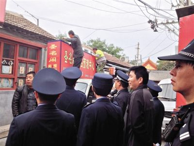 昨日下午,東城區(qū)工商、城管、公安等部門,對(duì)雍和宮附近的預(yù)測中心進(jìn)行清理整頓,站在車頂?shù)膬擅と苏鸪患摇邦A(yù)測中心”的招牌。因雍和宮、白云觀等文化景點(diǎn)外聚集大量算命先生,被媒體稱為“算命一條街”。本版攝影/新京報(bào)記者 李寧 攝