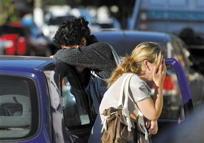 27日，遇難者親友在火災(zāi)現(xiàn)場旁哭泣。