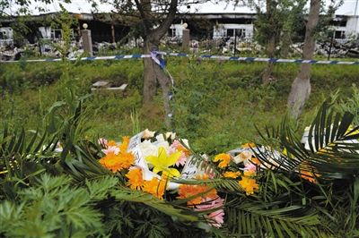 昨日，吉林省德惠市吉林寶源豐禽業(yè)有限公司燃燒事故現(xiàn)場(chǎng)警戒線外，遇難者家屬在路邊擺放了花圈祭奠逝去的親人。吳江 攝