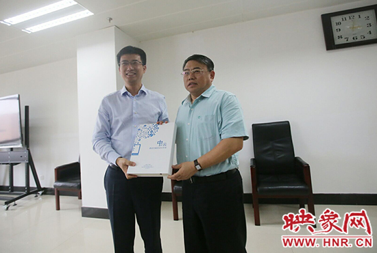 阿里云計算總裁胡曉明向河南省新聞出版廣電局局長朱夏炎遞交《中原云平臺交付手冊》。