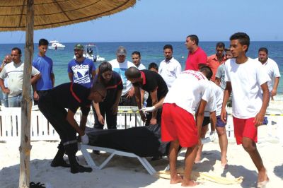 6月26日，在突尼斯蘇塞，救生員和醫(yī)務(wù)人員在發(fā)生襲擊事件的海灘運送一名死者的遺體。新華社發(fā)