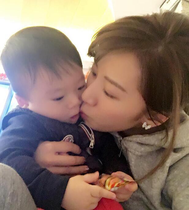 照片中李念狂吻兒子，小寶貝自顧自地玩著。