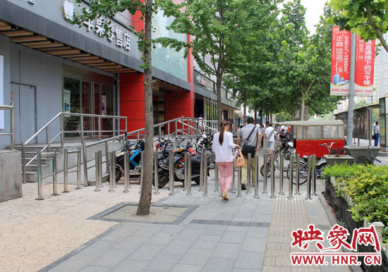 圖中道路左側的無障礙通道被鋼管隔離,右側的盲道也被侵占。