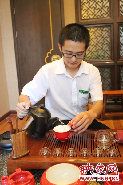 1、水壺里的水煮沸，李克勤把茶葉放進茶荷里，準備溫杯沖茶