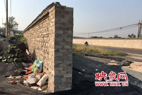 一墻之隔，一邊是道路，一邊是垃圾和荒草，市民質(zhì)疑其為遮羞墻。