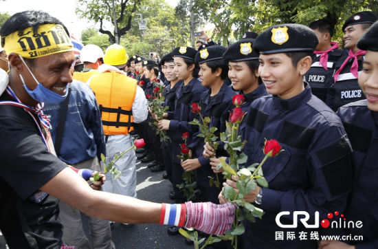 2013年12月03日,曼谷總理府與曼谷警署允許反政府示威民眾進(jìn)入,雙方進(jìn)入暫時“停戰(zhàn)”狀態(tài)迎接泰王生日。曼谷警察總署,女警們手持鮮花送給反政府示威民眾。圖片來源:Manish Swarup/東方IC