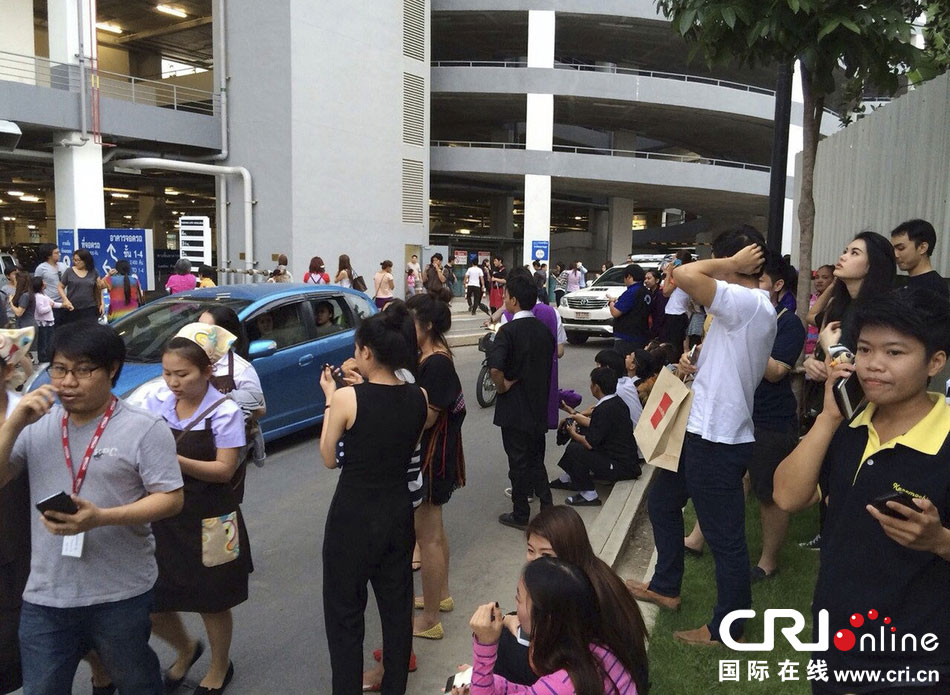 當(dāng)?shù)貢r間2014年5月5日，泰國清萊，工人們站在一棟大樓外避難。