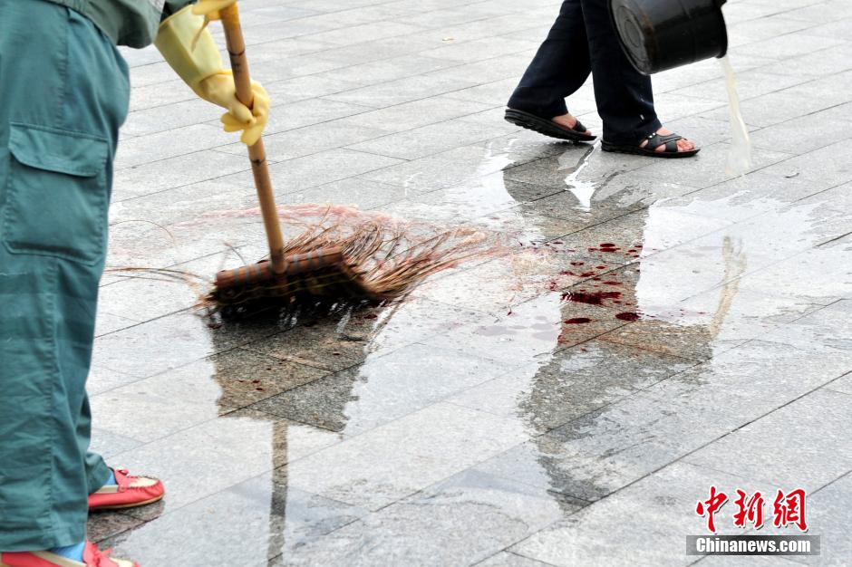 圖為環(huán)衛(wèi)工人在清理案發(fā)地點的血跡。