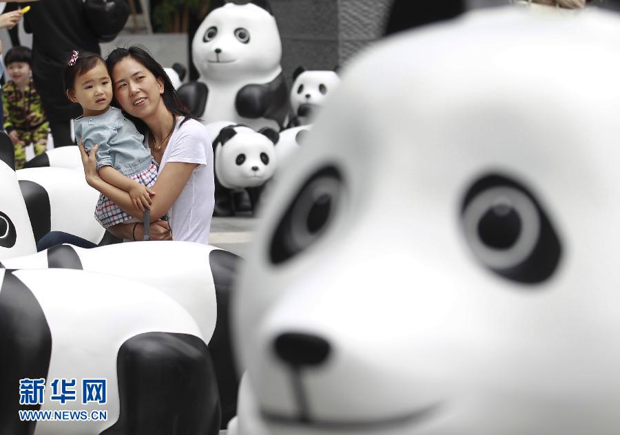 6月2日，一位家長(zhǎng)帶著孩子在上海街頭和大熊貓模型合影。