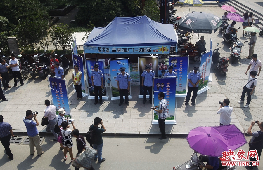 執(zhí)法人員用宣傳牌圍擋占道經(jīng)營(yíng)攤位。