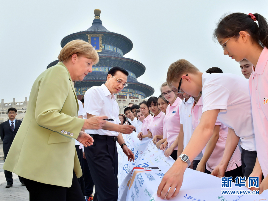 李克強(qiáng)同默克爾在紀(jì)念橫幅上簽名。