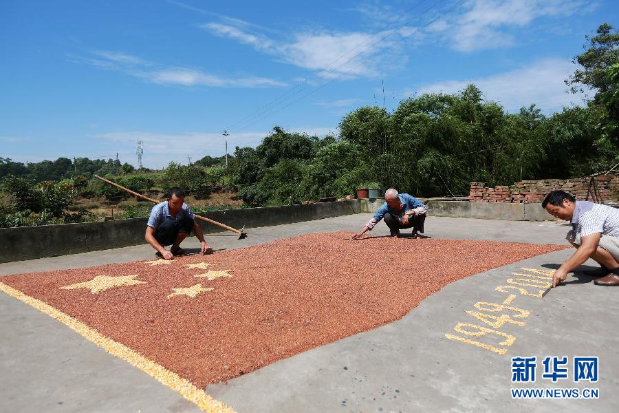 村民馬玉明（左一）用豐收的高粱和玉米在院壩里擺國旗為祖國慶生。