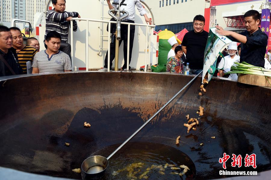 工作人員向大鍋內(nèi)加入油和姜等烹飪調(diào)料。 圖片來源：CFP視覺中國(guó)