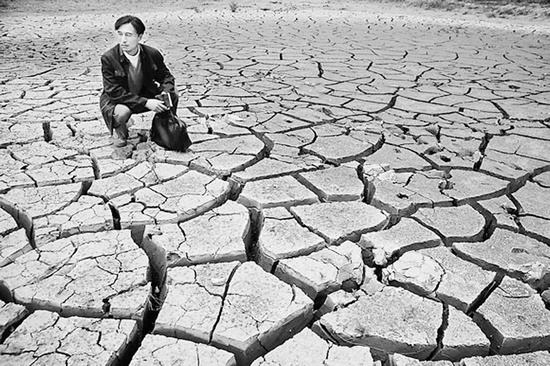 蹲在干涸的田地里，焦裕祿為饑餓的百姓揪心不已 《焦裕祿》劇照